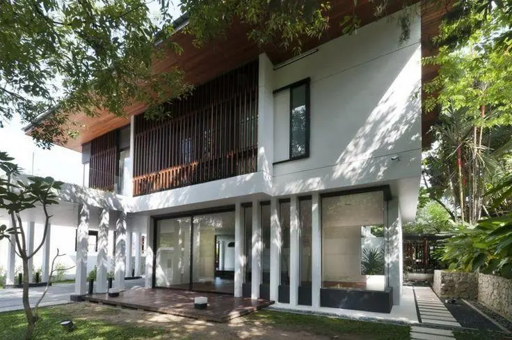Rumah dua tingkat berdinding putih dengan bilah kayu menegak dan pintu kaca